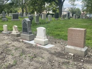 Five gravestones are placed back in place on a new concrete footing.